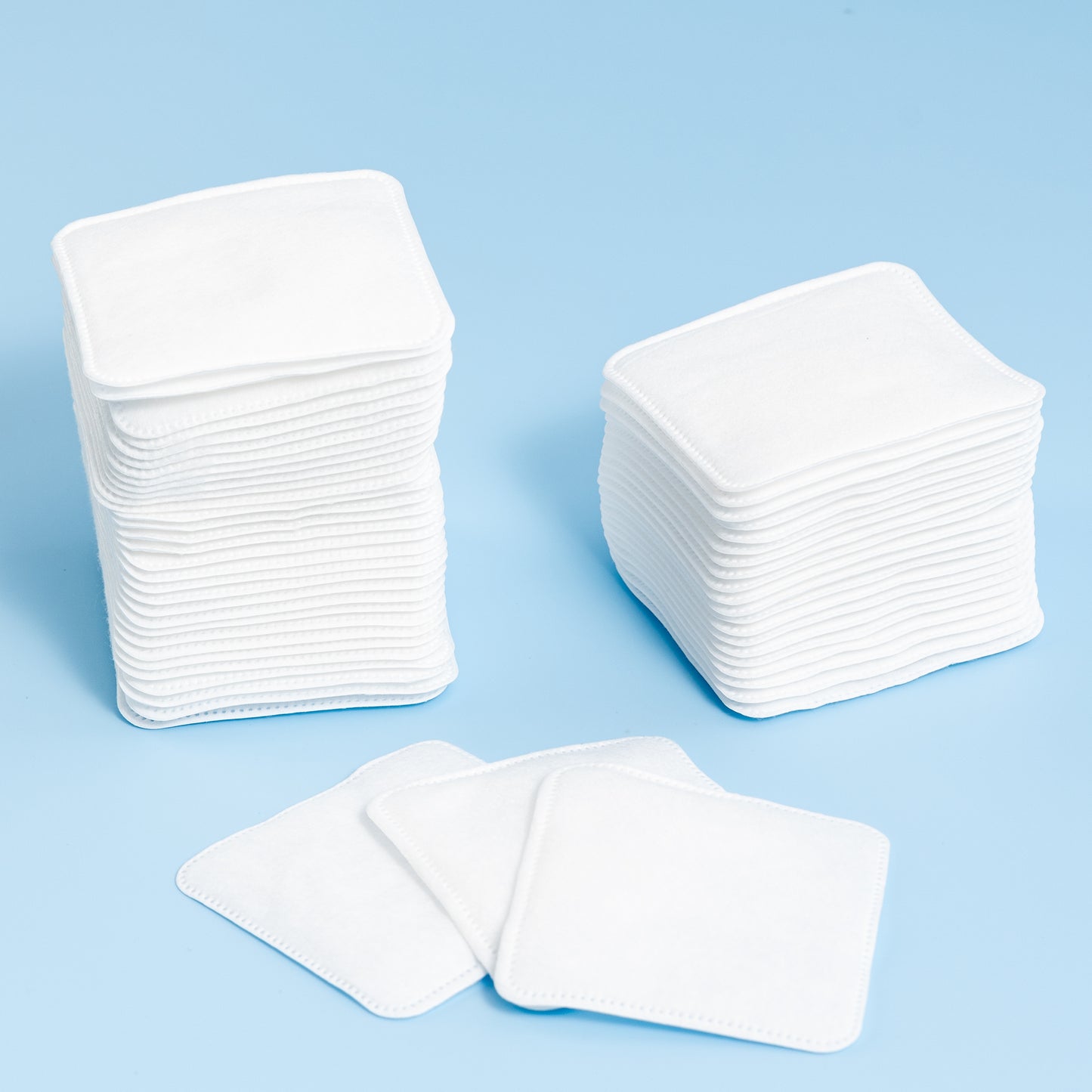 Stacks of white cotton pads on a light blue background